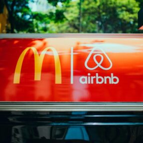 Bright sign showcasing recognizable logos on a vehicle's roof with blurred trees in the background.